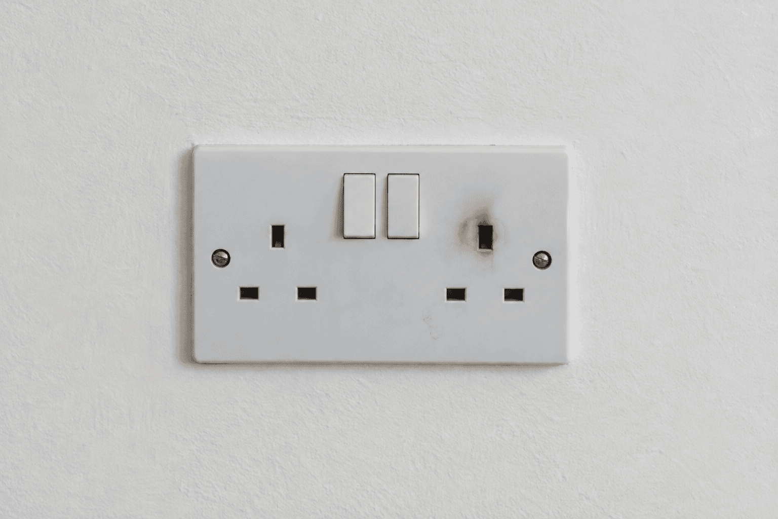 Illustration of an electrical emergency warning sign: a scorched socket with its cover closed.