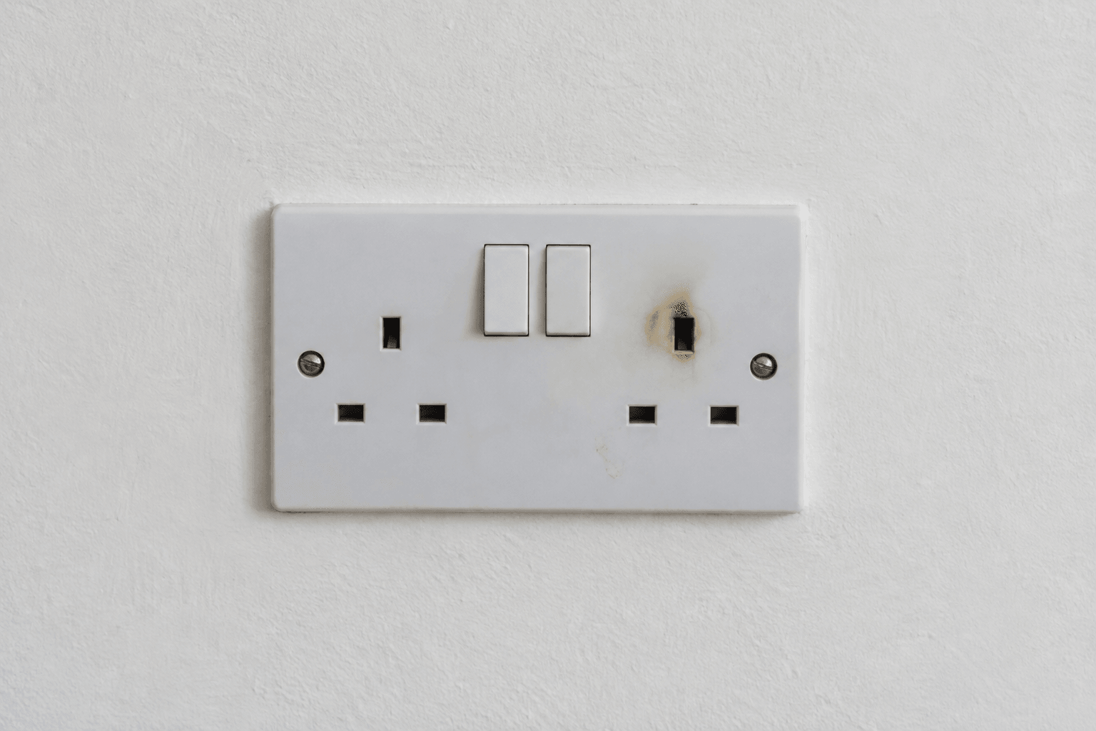 Illustration of an electrical emergency warning sign: a scorched socket with its cover closed.